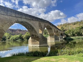 Arch bridge over river against sky