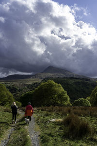 Rear view of people walking on mountain against sky