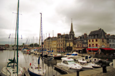 Boats moored in harbor against sky