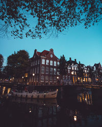 Buildings by canal against sky at night