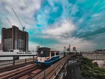 Train on road in city against sky