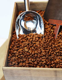 High angle view of roasted coffee beans and spatula in crate