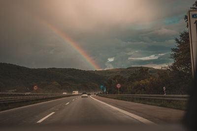 Rainbow over highway against sky