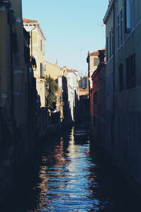 Canal amidst buildings in city against sky