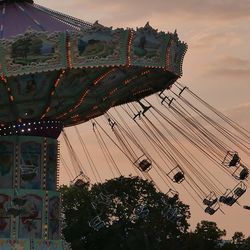 Low angle view of carousel against sky at sunset