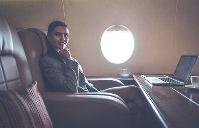 Portrait of smiling businesswoman sitting in airplane