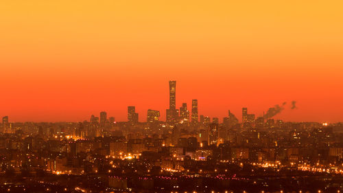 Illuminated cityscape against sky during sunset