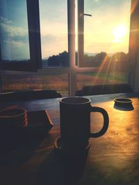 Coffee cup on table against sunset sky