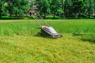 Electric hand lawn mower at stadium. lawn care on sports field.