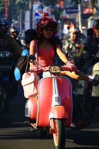 Portrait of woman with motor scooter on street in city