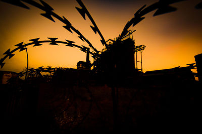 Silhouette plants on field against orange sky