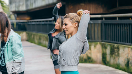 Woman runner stretching arms next to her female friends before training