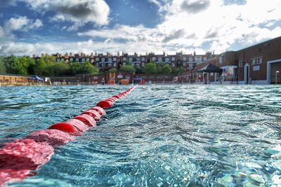Swimming pool by buildings against sky