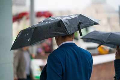 Man with umbrella walking on wet street