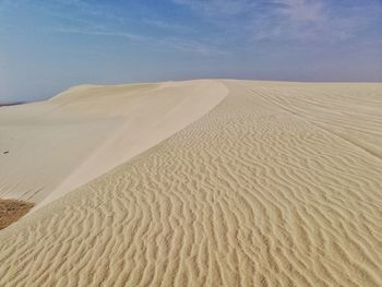 Sand dune in desert against sky