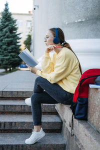Outdoor portrait of happy student girl, young woman listening to audio lessons