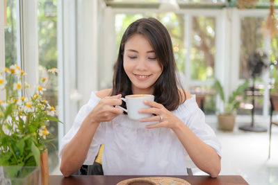 Young woman using phone while sitting on table