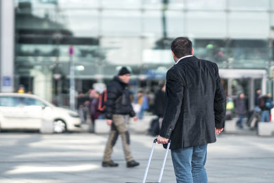 Rear view of man with luggage standing on road