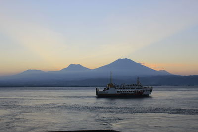 Fishing boat in sea against sky during sunset