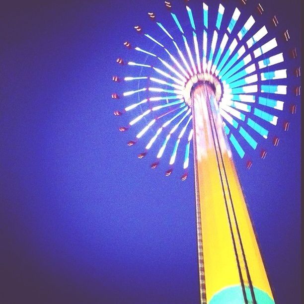 low angle view, amusement park, arts culture and entertainment, amusement park ride, blue, illuminated, multi colored, ferris wheel, clear sky, sky, lighting equipment, fun, night, art, no people, decoration, pattern, outdoors, circle, creativity