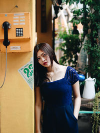 Portrait of young woman standing by building