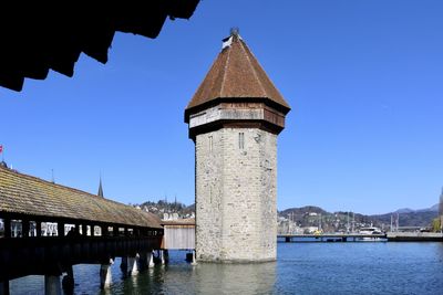 Low angle view of river amidst buildings against clear blue sky