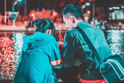 Rear view of couple sitting in city at night