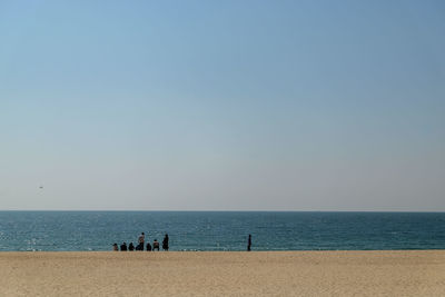 People on beach against clear sky