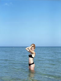 Young woman standing in sea against sky