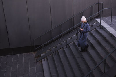 Young woman walking down stairs and using phone