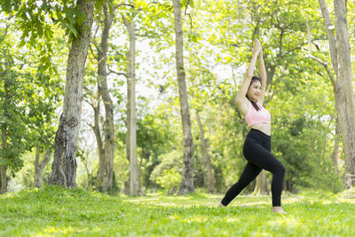 Full length of young woman exercising on field at park