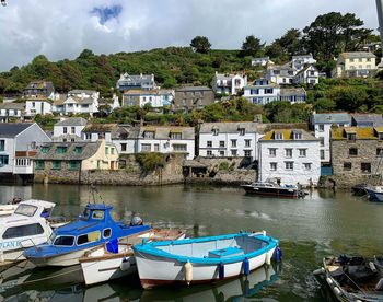 Sailboats moored in river by town against sky