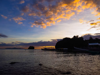 Silhouette boats in sea against sky during sunset