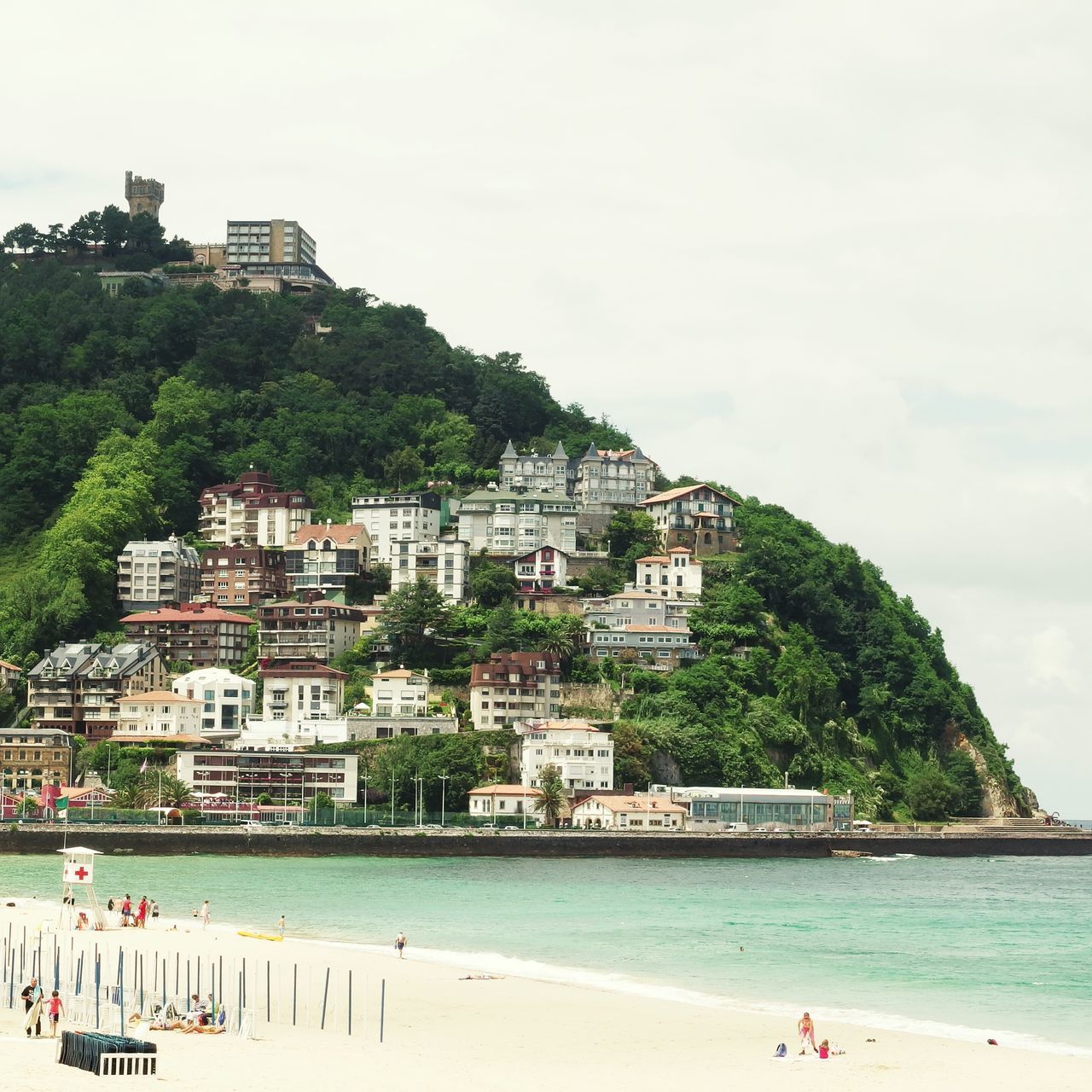 water, sea, building exterior, architecture, beach, built structure, large group of people, leisure activity, lifestyles, shore, vacations, sky, tree, tourist, person, men, coastline, tourism, mixed age range