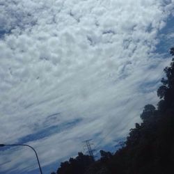 Low angle view of power lines against cloudy sky