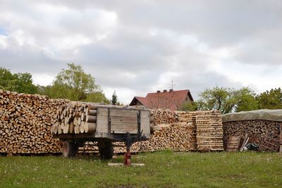 Stack of logs on field against sky