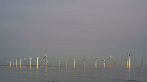 Wind turbines in sea against sky