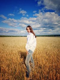 Full length portrait of smiling woman standing on field