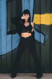 Portrait of woman standing against black background