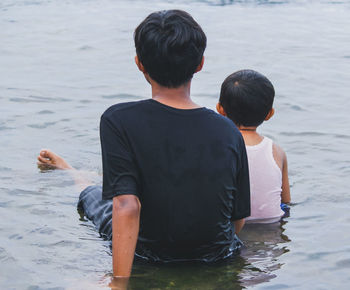 Rear view of two boys swimming in lake