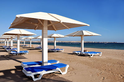 Deck chairs on beach against blue sky