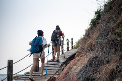 Rear view of men walking on staircase against clear sky