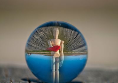 Reflection of human figurine seen in crystal ball