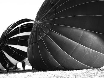 People preparing hot air balloons against clear sky