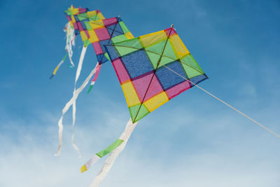 Low angle view of kites flying against sky