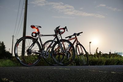 Bicycle parked on road against sky during sunset