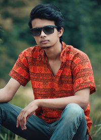 Young man wearing sunglasses sitting outdoors