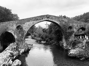 Arch bridge over river against sky