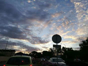 Cars on street against dramatic sky