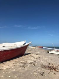 Boat moored on beach against sky